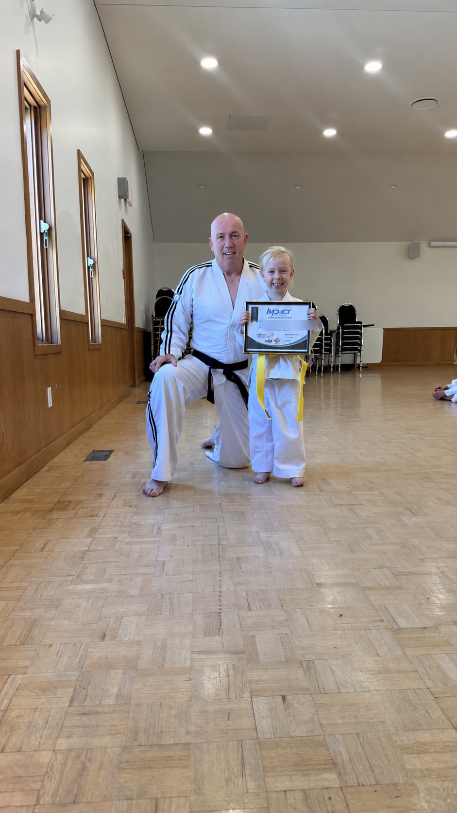 Master Michael Barker presenting a student achievement certificate with identifying details blurred